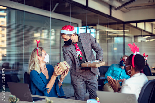 Colleagues exchanging Christmas gifts in office during holiday celebration photo