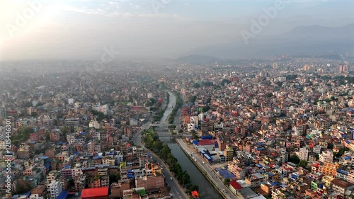 Aerial view of a river winding through the city of Kathmandu, Nepal. Drone clip moving forward and right of the city during daytime with a haze in the sky.