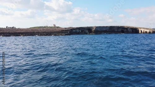 Rocky coast of the northern part of the island of Malta as seen from the sea, with the island of Comino in the background