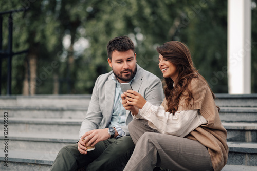 Two business colleagues enjoying a break and sharing content on smartphone