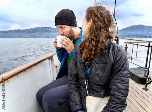 A man sips hot cocoa on a ferry in Switzerland, as his wife looks on. photo