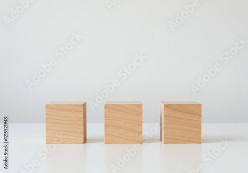 Three empty wooden cube blocks lined up on a table on a white background with copy space.
