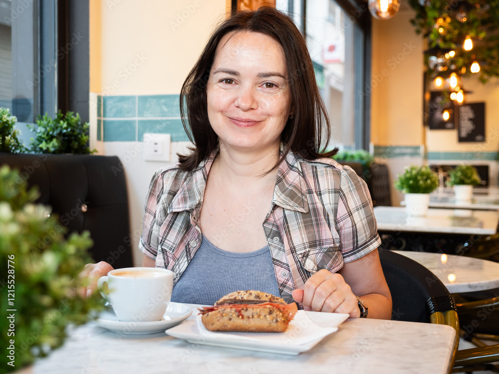 In deserted cafe, young woman ordered usual popular European breakfast - cup of coffee and sandwich with sausage products In deserted cafe, young woman ordered usual popular European breakfast - cup of coffee and sandwich with sausage products