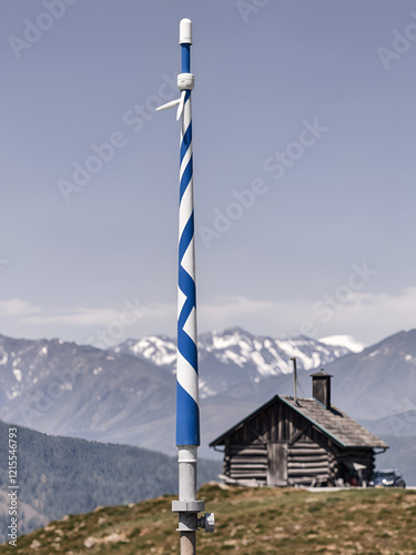 A wind cone with white and blue stripes on the background of a mountain landscape. An outbuilding on the background of a mountain range. The wind in the mountains. Wind direction detection device photo