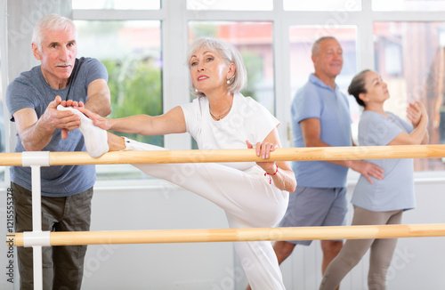 Male choreographer teaches elderly ballet lovers to stand in the grand batman position photo