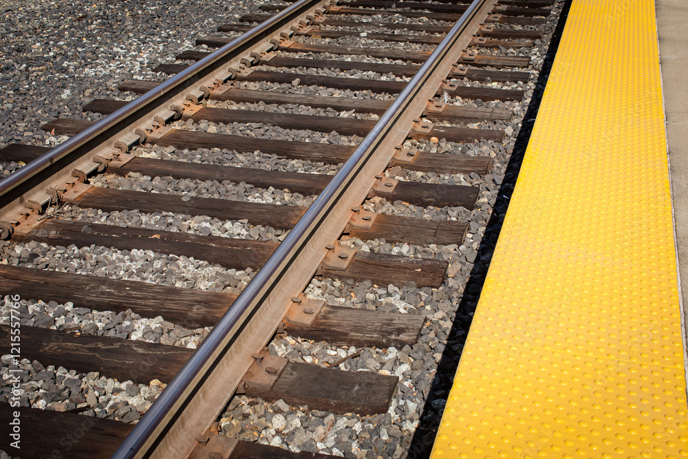 Top view of ADA compliant detectable warning pavers on a train platform. Truncated dome ADA tiles. Bump texture tiles on a platform. Closeup of train tracks with a safety line with yellow bump texture Top view of ADA compliant detectable warning pavers on a train platform. Truncated dome ADA tiles. Bump texture tiles on a platform. Closeup of train tracks with a safety line with yellow bump texture