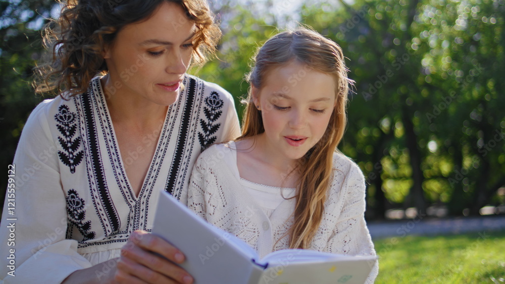 Fototapeta premium Woman parent daughter reading book sitting nature closeup. Mother kid resting