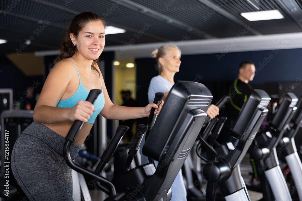 Active young woman training at elliptical machine in gym Active young woman training at elliptical machine in gym