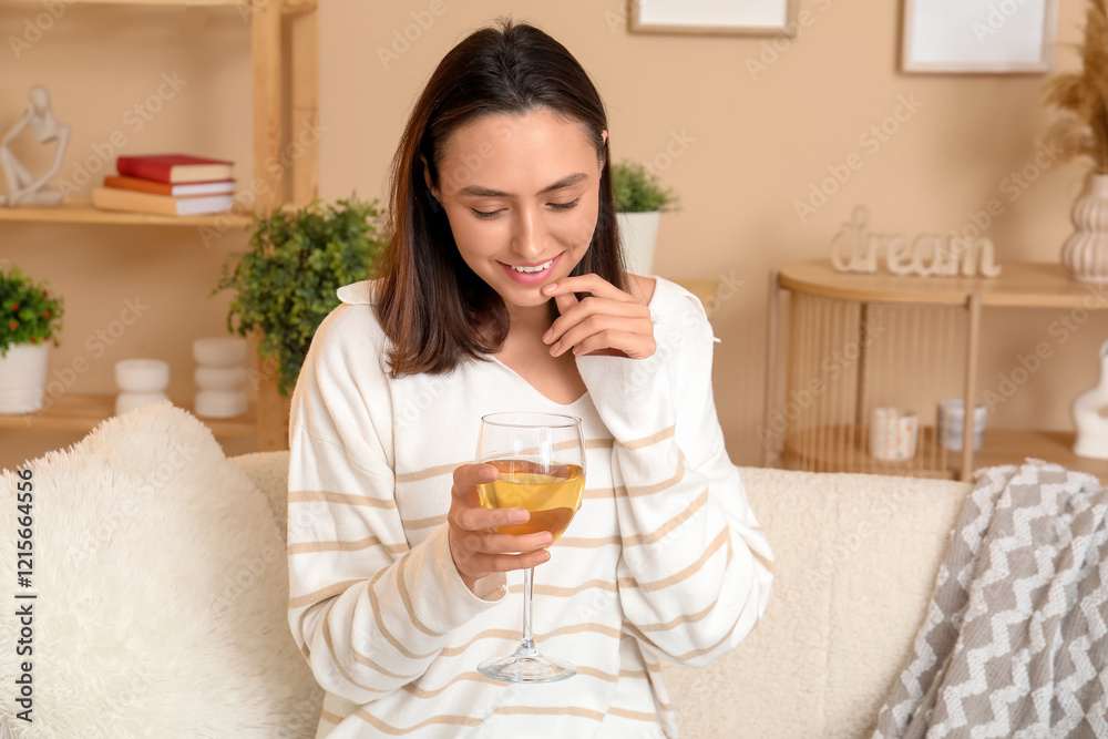 Beautiful woman with glass of wine sitting on sofa at home Beautiful woman with glass of wine sitting on sofa at home