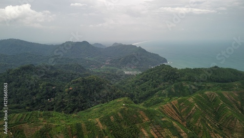 Drone view of Embung Srati or Embung Silayur Kebumen, a large water reservoir on green hills with forests and trees and rows of hills around it. photo