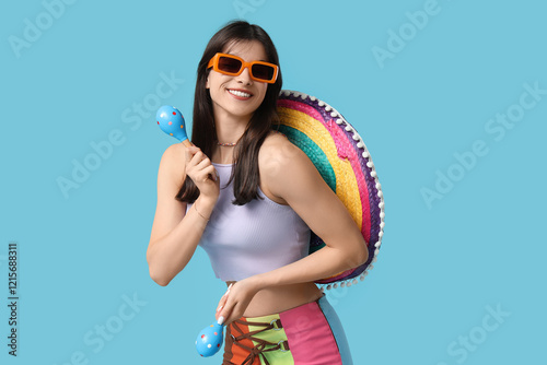 Young woman with colorful sombrero and maracas on blue background. Cinco de Mayo celebration