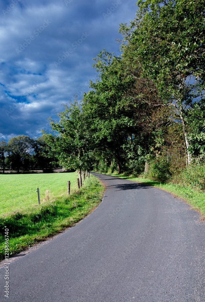 A road in the countryside with some clouds in the background A road in the countryside with some clouds in the background