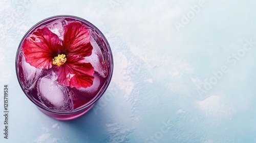 Colorful cocktail with hibiscus flower and ice cubes on blue background Copy Space photo