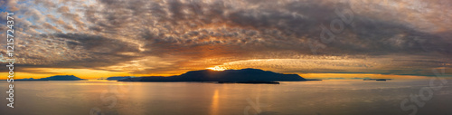 Dramatic and colorful sunset over Orcas Island in the San Juan Islands archipelago of Washington State. Aerial drone view of an amazing cloudscape as seen from Lummi Island located in the Salish Sea.