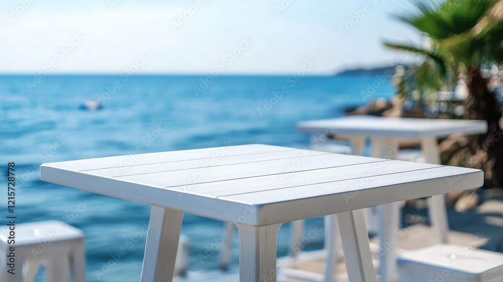 Fototapeta premium White Wooden Table on Bar Counter Against Blurred Blue Sea Background and Green Palm Fronds in Bright Sunlight