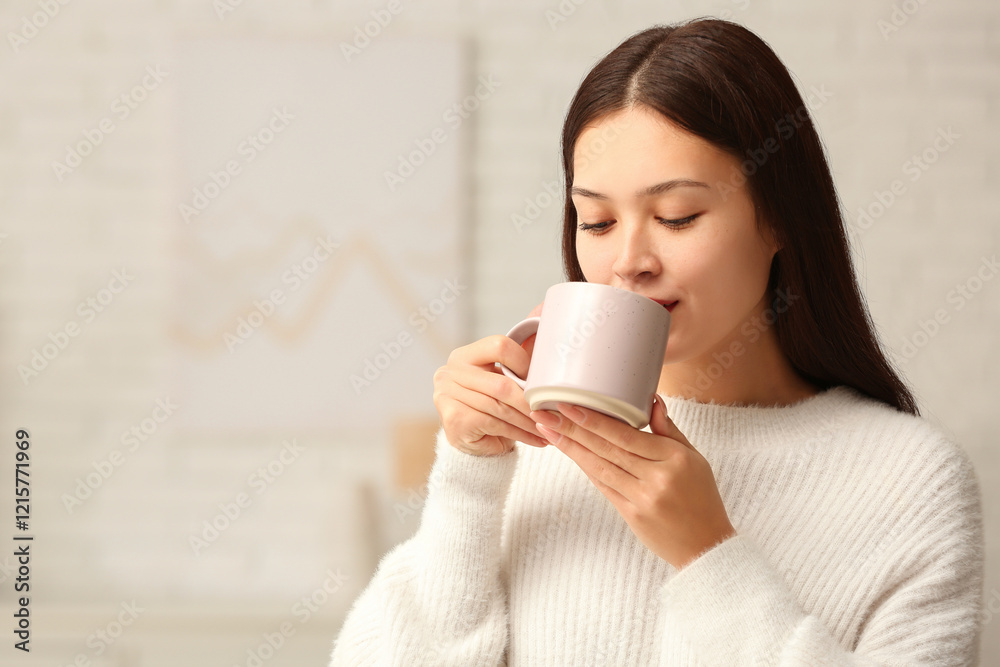 Beautiful young Asian woman drinking hot tea in living room Beautiful young Asian woman drinking hot tea in living room