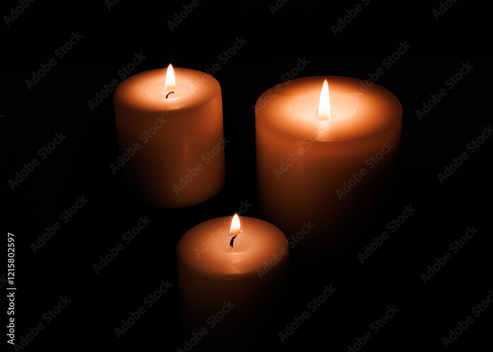 Three votive candles burning in a dark setting. Very moody romantic or religious feeling. Natural yellow and orange color. Three votive candles burning in a dark setting. Very moody romantic or religious feeling. Natural yellow and orange color.
