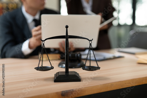 A focused, close-up shot of a black metal justice scale standing on a wooden desk, symbolizing law and equity.