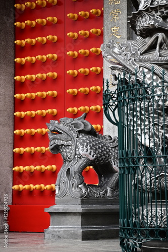 The red gate of Xingtian Temple stands as a striking symbol, adorned with glowing doornails and flanked by powerful stone lions and intricately carved dragon pillars, exuding cultural richness. photo