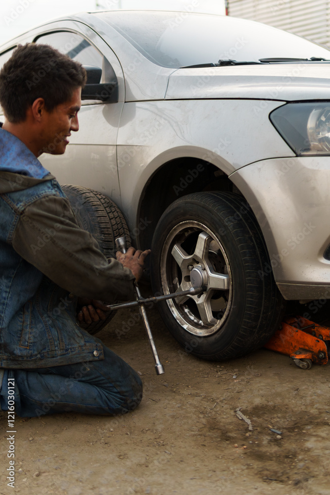 Man Removing Flat Tire with Cross Wrench Man Removing Flat Tire with Cross Wrench
