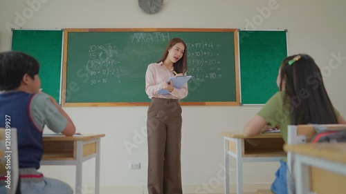 Asian female teacher educating group of students at elementary school. 