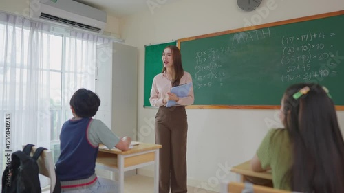 Asian female teacher educating group of students at elementary school.