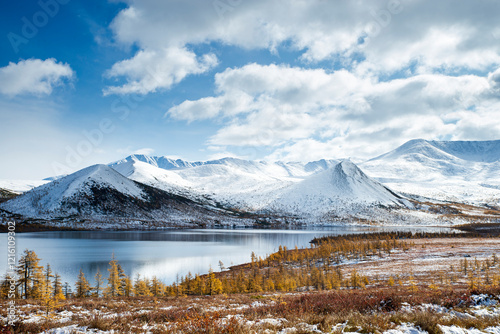 Russia. Magadan Region. Beautiful Lake Momontay against the backdrop of a snowy mountain range. Late autumn in the vicinity of Lake Momontay.