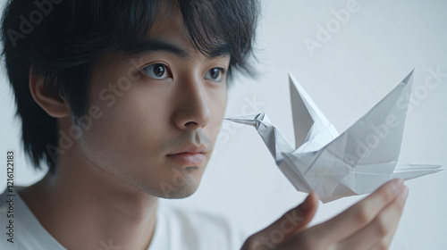 a man holding a paper bird in his hand photo