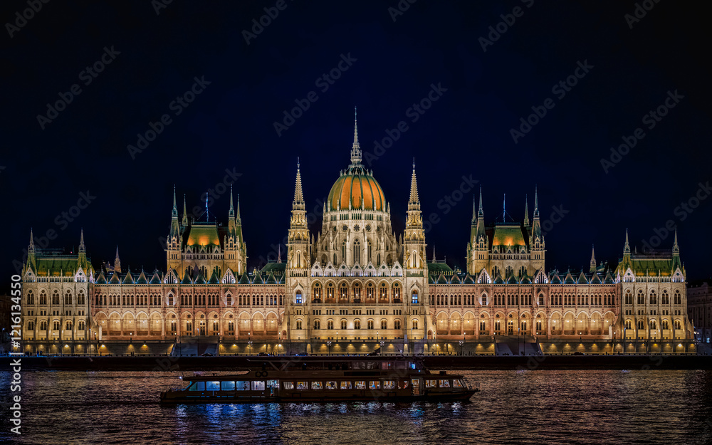 illuminated Hungarian Parliament Building during the blue hour, with a boat cruising on the Danube River