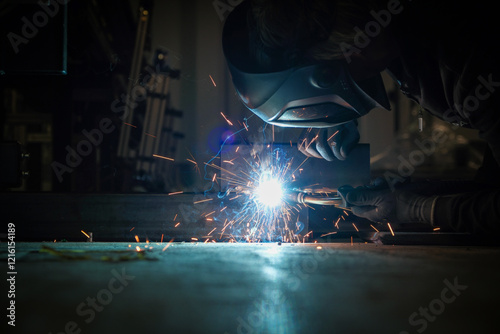 Obraz na płótnie a person wearing a welding mask works on metal with a welding torch, creating sparks through the welding process w salonie