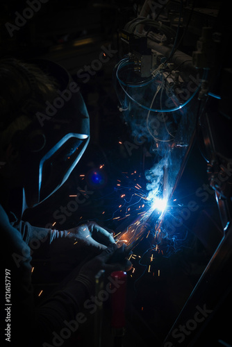 Obraz na płótnie a person wearing a welding mask works on metal with a welding torch, creating sparks through the welding process w salonie