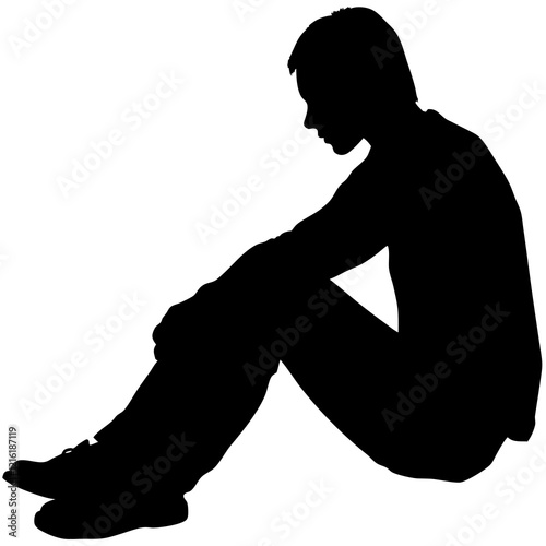A man is sitting on the ground. He is wearing a black shirt and black pants. He is looking down