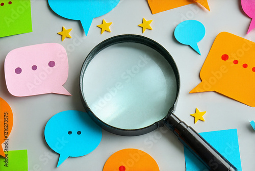 magnifying glass with a speech bubble in its center. The magnifying glass is placed on a white surface that has scattered around it colorful speech bubbles and stars