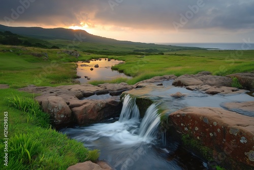 Serene Sunset Over Tranquil Stream Flowing Through Lush Green Landscape with Gentle Rock Formations