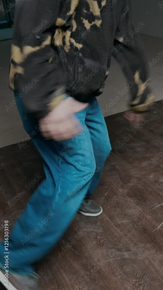 Vertical handheld shot of talented Caucasian gen Z b-boy in streetwear improvising breakdance while performing creative top rock moves indoors Vertical handheld shot of talented Caucasian gen Z b-boy in streetwear improvising breakdance while performing creative top rock moves indoors