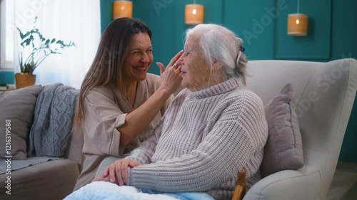 Adult happy daughter whispering funny news to 80s senior mother while spending time at home together