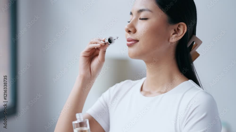 Video of cheerful woman holding a bottle of essential oil while testing it sitting on a couch at home. Video of cheerful woman holding a bottle of essential oil while testing it sitting on a couch at home.