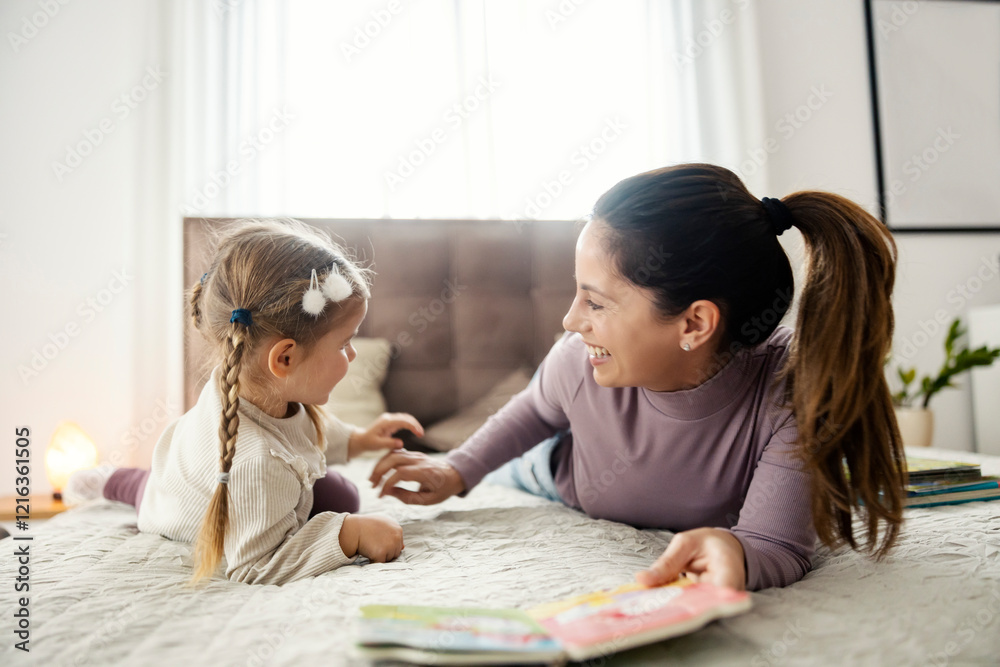 A mother lying in bed with her daughter and having during their story time at home. A mother lying in bed with her daughter and having during their story time at home.