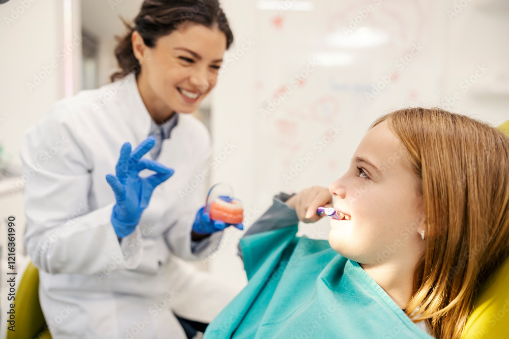 Smiling girl demonstrated proper teeth way to brush teeth at dentist office while dentist gesturing okay. Smiling girl demonstrated proper teeth way to brush teeth at dentist office while dentist gesturing okay.