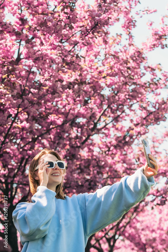 Obraz na płótnie happy woman taking selfie on the phone in front of blooming sakura w salonie