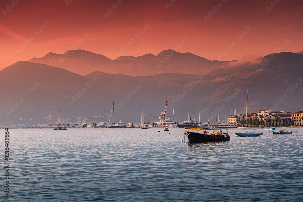 Scenic view of Tivat cityscape and harbor in Montenegro, with the bay of Kotor and mountains in the background during a colorful sunset