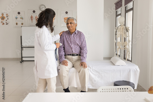 Your heart is healthy. Happy smiling doctor put hand on shoulder of aged patient pensioner sitting on medical couch after cardio checkup glad to inform about good health state low cardiovascular risks