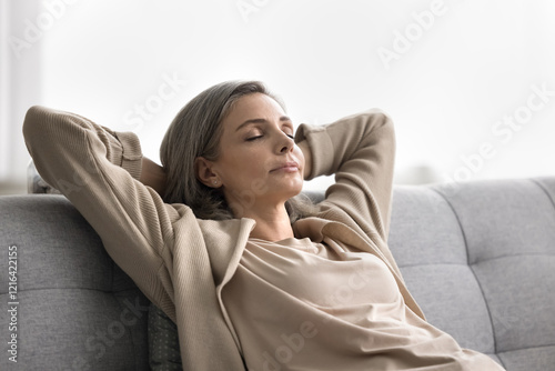 Stress free serenity. Head shot portrait calm tranquil older age woman spend quiet lazy moment of personal retreat at home recline on sofa with hands behind head keep eyes closed enjoy peace solitude