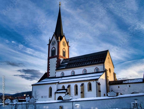 Basilika Mariapfarr im Winterlicht.. Die Kirche beeindruckt mit ihrer traditionellen Architektur, einem hohen Turm und einem blauen Himmel als Hintergrund