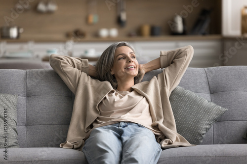 Pleasure of doing nothing. Serene mindful older adult woman relax sitting on comfortable couch at warm cozy home breath fresh conditioned air lost in good peaceful thoughts feel calm happiness harmony
