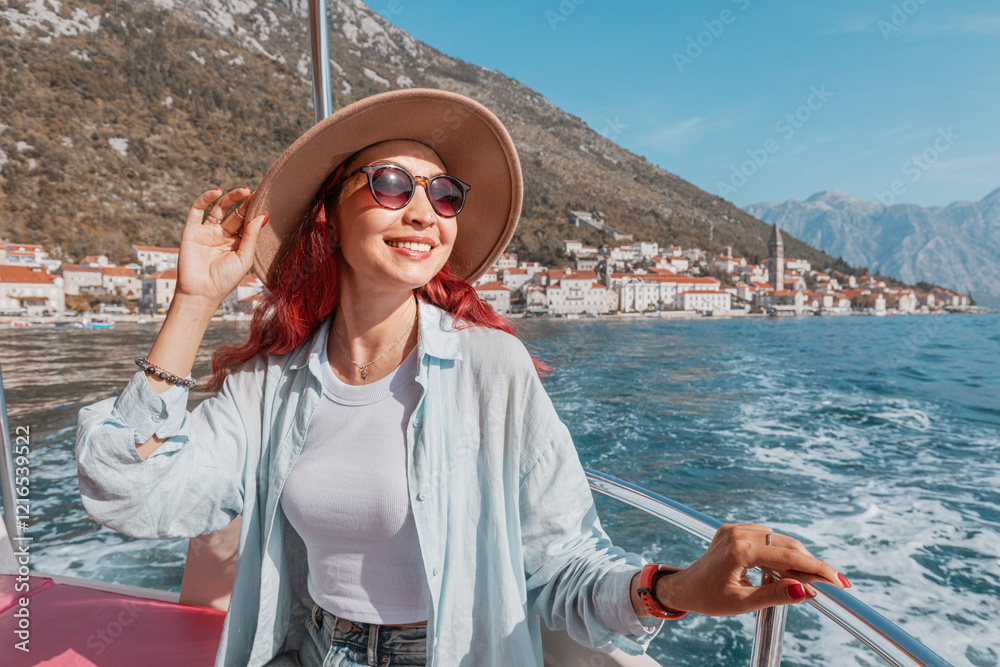 Young woman enjoying a boat trip in the bay of Kotor, with the picturesque town of Perast in the background