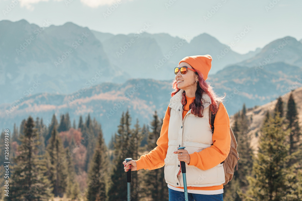 Hiker with trekking poles admiring mountain landscape in autumn