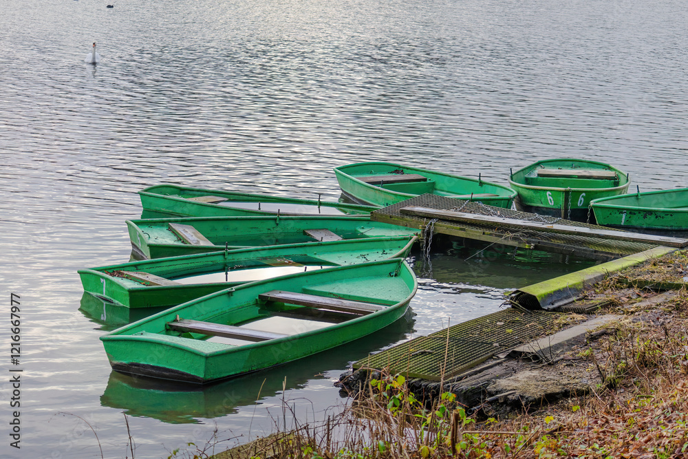 A row of green boats are sitting in the water