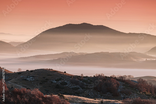 Obraz na płótnie Low lying fog covering layers of hills at dawn with a beautiful orange sky w salonie
