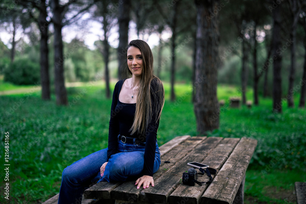 Chica joven delgada vloggeando con cámara por zona verde con arboles